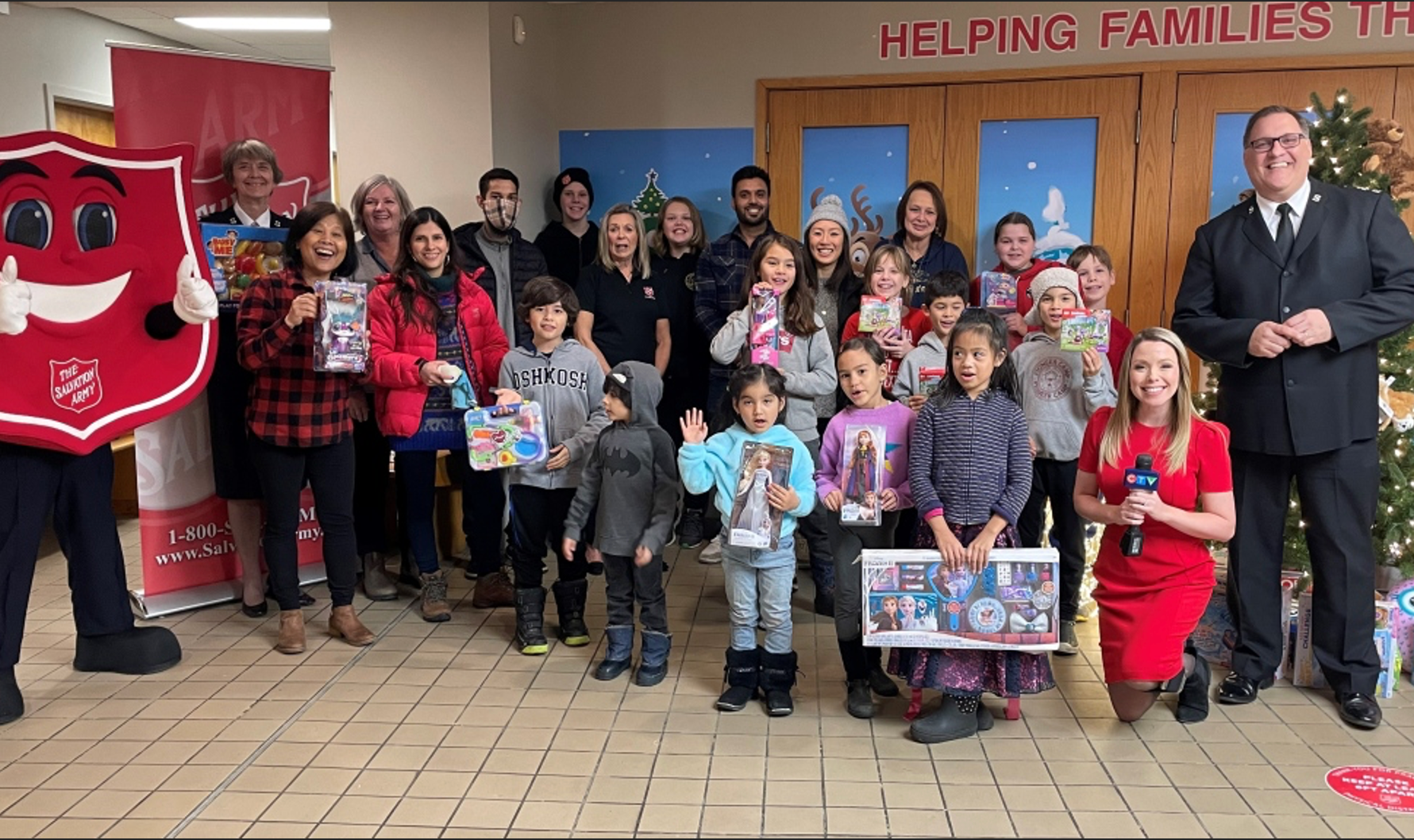 Group of people and children standing together in the Salvation Army community space holding toys.